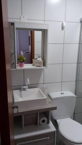 a bathroom with a sink and a toilet and a mirror at Apto da Karla em Canela 4 pessoas in Canela