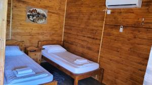 two beds in a room with wooden walls at La Podul Gornii in Gornea