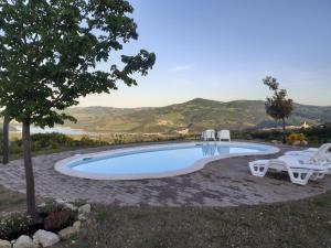 a swimming pool with two chairs and a tree at Le Terre Del Sacramento in Guardialfiera