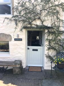 a white door on a white house with a bench at Westside Cottage, Newby Yorkshire Dales National Park 3 Peaks and Near the Lake Disrict, Pet Friendly in Newby