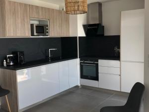 a kitchen with white cabinets and a black counter top at VILLA GEORGES in Le Grau-du-Roi