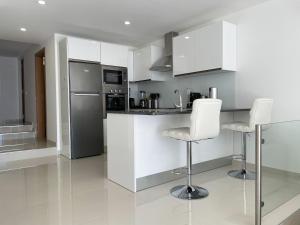 a kitchen with white cabinets and white bar stools at Casa Rosa - Vilamoura in Vilamoura