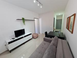 - un salon avec un canapé et une télévision dans l'établissement Belo Apartamento Eldorado II Master Collection, à Passo Fundo