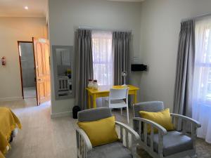 a living room with a yellow table and chairs at Cape Karoo Guesthouse in Beaufort West