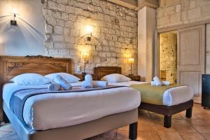 2 camas en un dormitorio con pared de piedra en Hôtel La Muette, en Arles