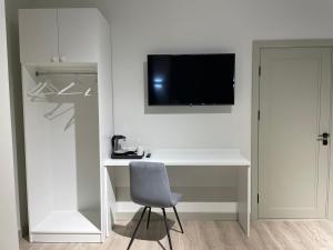 a white desk with a chair and a television on a wall at SB River Hotels in Atyrau