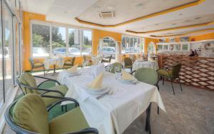 a restaurant with white tables and chairs and windows at Mediterranean Guest House Balkan in Budva