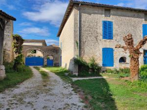an old building with blue doors and a dirt road at LE LOGIS DE LA PIERRE in Périgné