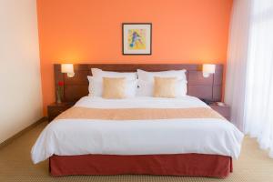 a bedroom with a large bed with an orange wall at CONTINENTAL ALTAMIRA in Caracas