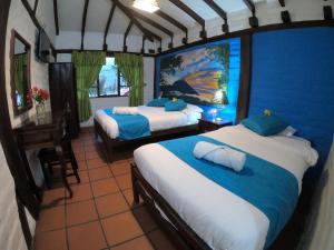 a bedroom with two beds with blue walls and a table at Hostal Inti Luna in Baños