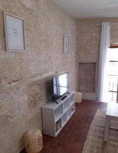 a living room with a tv on a white cabinet at Le Quatrième - Avignon Intramuros in Avignon