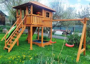 a tree house with a slide and a swing at Apartament KARINA in Tylicz