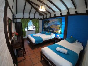 una camera da letto con due letti e una parete blu di Hostal Inti Luna a Baños