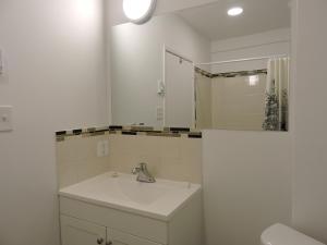 ein weißes Badezimmer mit einem Waschbecken und einem Spiegel in der Unterkunft Almo Court Motel in Cranbrook