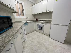 cocina con armarios blancos y nevera blanca en Apartamento para 7 personas en Calafell, Barcelona., en Calafell