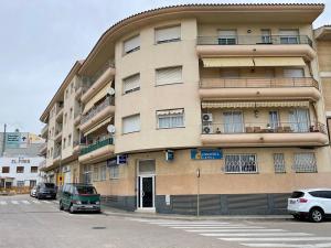 un edificio alto con coches estacionados frente a él en Apartamento para 7 personas en Calafell, Barcelona., en Calafell