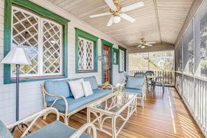 a porch with blue chairs and a ceiling fan at Anna's Cottage in Saugatuck