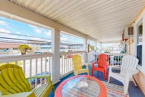 a porch with colorful chairs and a table at Brooklyn's Casa Rosa & Hitch Apartment in Ocean City