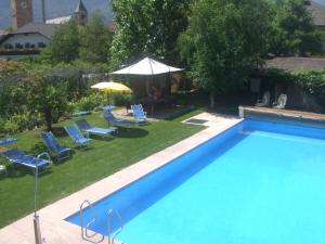 uma grande piscina com cadeiras e um guarda-sol em Pension Runer em Terlano