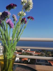 a vase filled with purple and white flowers on a table at Lido Funchal Apartment balcony sea view in Funchal