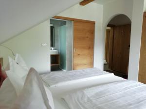 ein weißes Bett in einem Zimmer mit Spiegel in der Unterkunft Pension Runer in Terlan