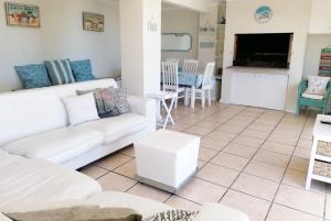 a living room with a white couch and a table at Orca View Melkbosstrand in Melkbosstrand