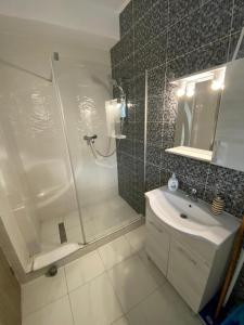 a white bathroom with a shower and a sink at Apartament Ella D25 Mackerel in Mamaia Sat/Năvodari +76 photos