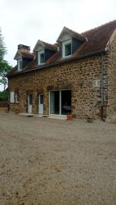 una casa de piedra con una gran ventana en el lateral. en maison en pierre de pays, en Ségrie