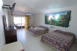 a hotel room with two beds and a tv at Posada Real in Rincon de Guayabitos