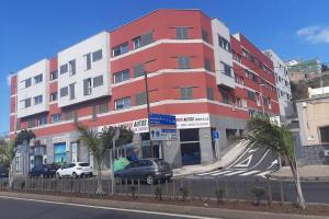 un edificio rojo y blanco con coches estacionados frente a él en Apartamento moderno Timanfaya, en Santa Cruz de Tenerife