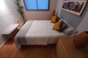 1 dormitorio con 1 cama blanca grande con almohadas amarillas en Apartamento moderno Timanfaya, en Santa Cruz de Tenerife