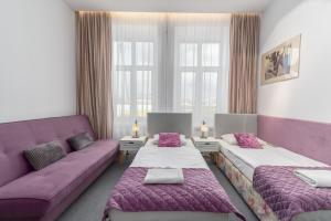 Pokój z 2 łóżkami i fioletową kanapą w obiekcie Nasze Kamienice Studio 3 5 7 w mieście Rzeszów