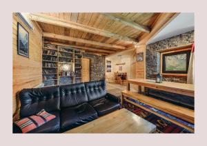 a leather couch in a living room with a stone wall at Kazbegi Hut in Kazbegi