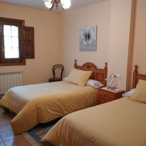 Casa Rural Leonor في San Ciprián: غرفة نوم بسريرين ومصباح على طاولة