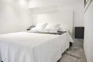 Una cama blanca con dos almohadas encima. en ALANDALUS Modern y Luxury, en Sevilla