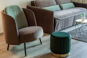 a chair and a stool in a living room with a couch at Stay COOPER l Tivoli in Bolzano