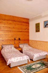 two beds in a room with wooden walls at Hajdu Lovasudvar Hortobágy in Hortobágy