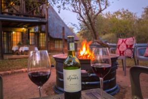 two glasses of wine sitting on a table next to a fire at Erdvark in Marloth Park