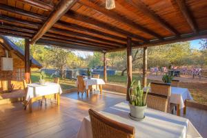 a patio with white tables and chairs and a wooden ceiling at Erdvark in Marloth Park