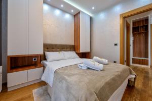 a bedroom with a large bed with towels on it at Lux Apartman Lea - Vila Esla 1 in Zlatibor