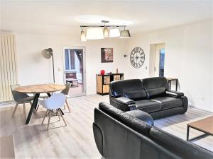 uma sala de estar com um sofá de couro preto e uma mesa em Greyhound - Grand Appartement centre-ville em Soissons
