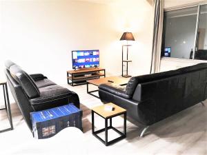 uma sala de estar com mobiliário de couro preto e uma televisão de ecrã plano em Greyhound - Grand Appartement centre-ville em Soissons