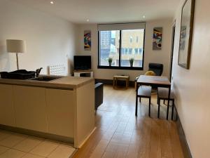 a kitchen and living room with a sink and a table at Liverpool City Princes Dock Apartment in Liverpool