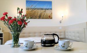 una mesa con dos tazas y un jarrón con flores en Harpun, en Władysławowo