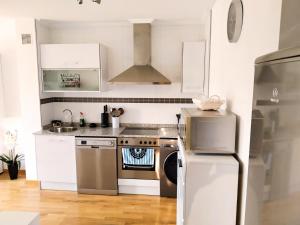 Una cocina con gabinetes blancos y un refrigerador de acero inoxidable. en APARTAMENTO KENITRA, en Avilés 3 fotos más