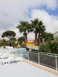un complexe avec des palmiers et une piscine dans l'établissement MOBIL HOME Climatisé 6 Personnes au Camping Marvilla Parks - Le Parc Des Septs Fonts, à Agde