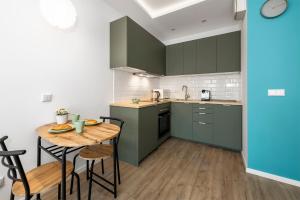 cocina con armarios verdes y mesa de madera en MYE Apartments - Ilumino, en Łódź