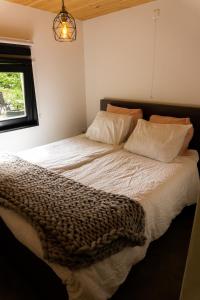 a bedroom with a bed with white sheets and a window at Het creijennest Gemeente 's-Hertogenbosch in Rosmalen