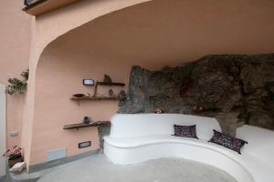 Sofá blanco en una habitación con pared de roca en Casa Claudia, en Ravello