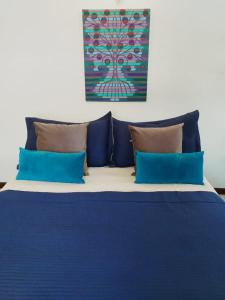 1 cama con almohadas azules y una pintura en la pared en Karma en San Martín de los Andes